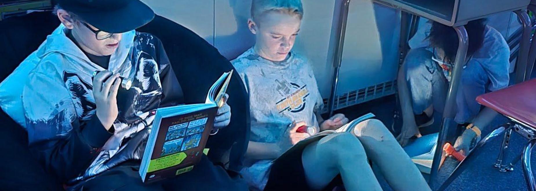 Boys reading in soft chairs with warm lighting, each focused on their books.