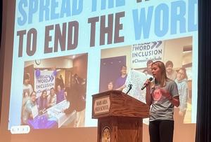 a girls standing at a podium in front of a projector screen