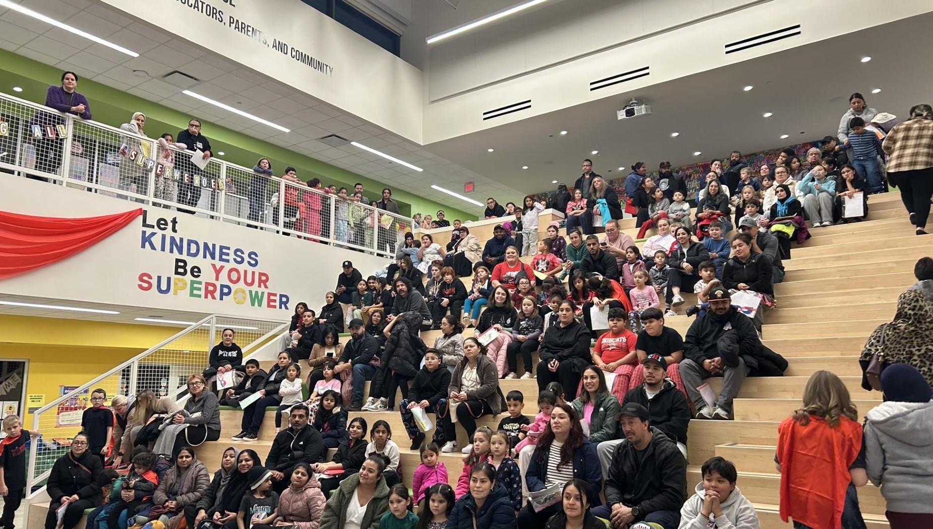 A diverse crowd of families gathered on the steps of a community space, engaging in an event.