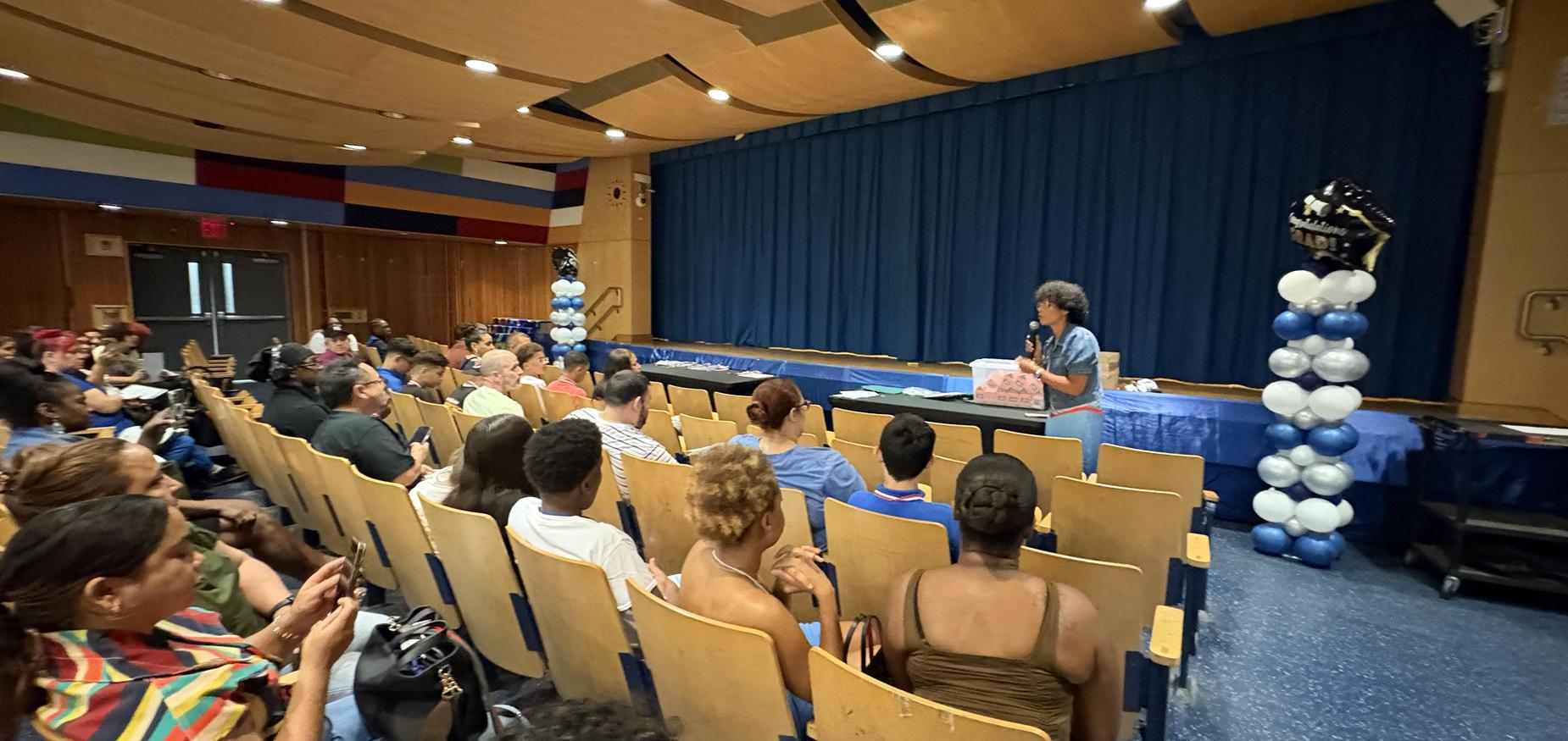 Principal speaking to students and parents in auditorium