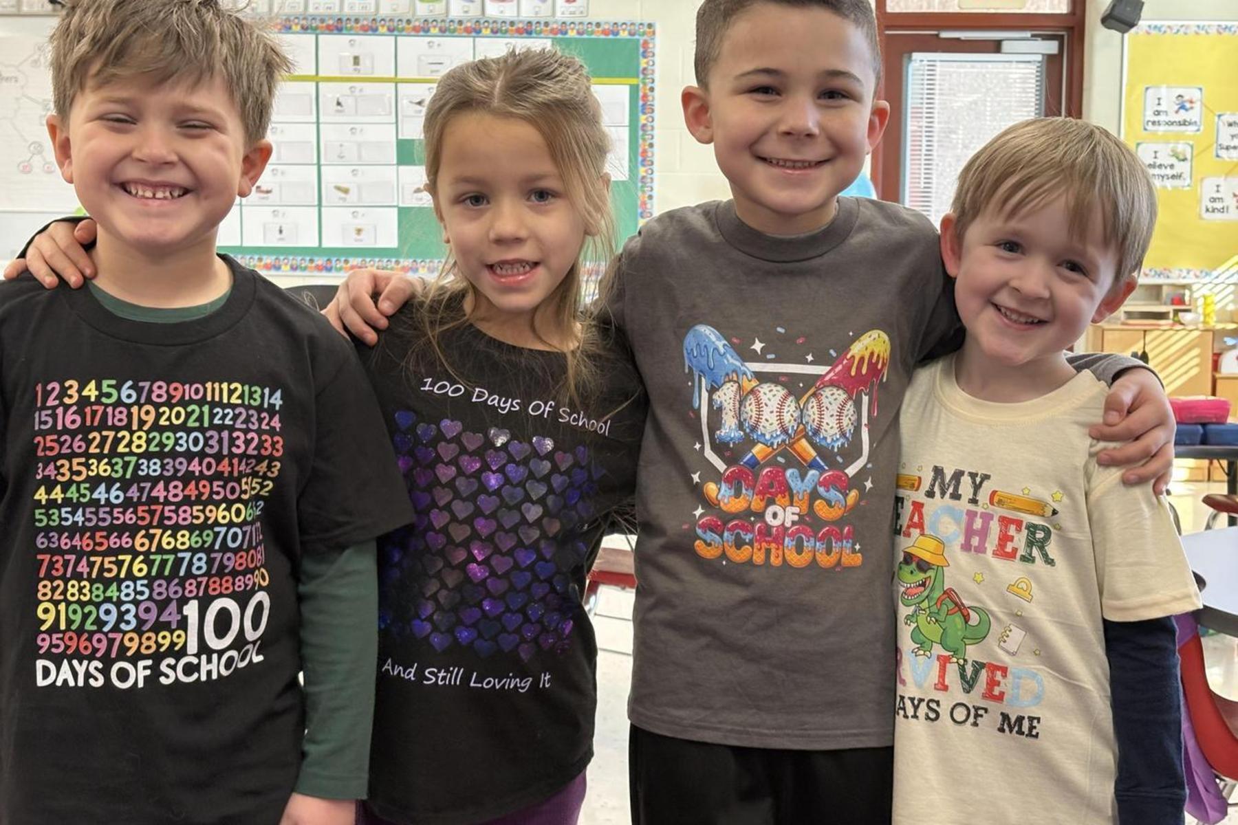 Four children in colorful shirts, smiling together at school.
