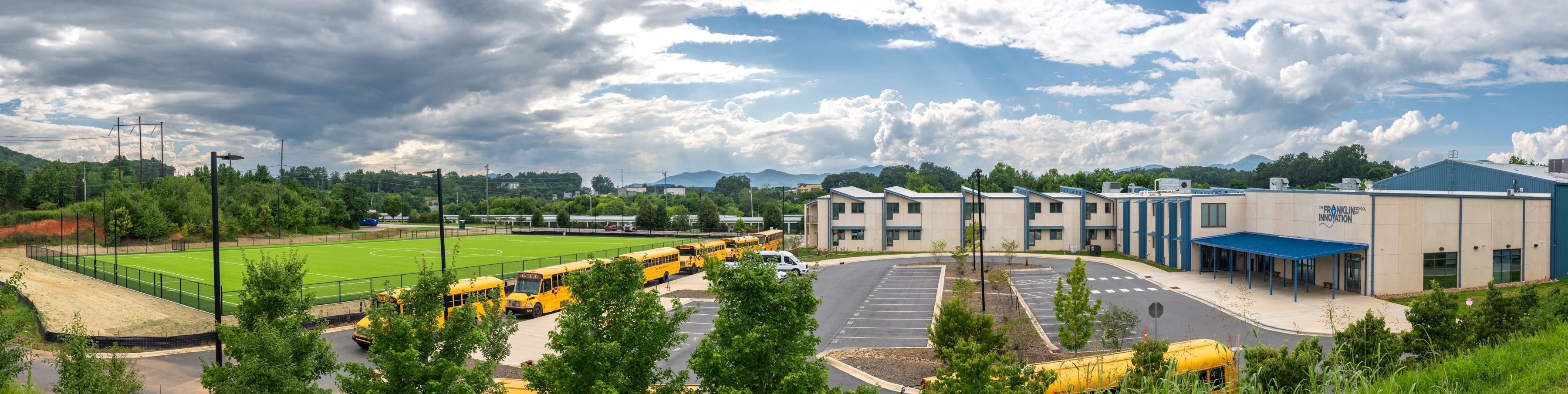Panorama of campus with the school building and athletic field on a spring day