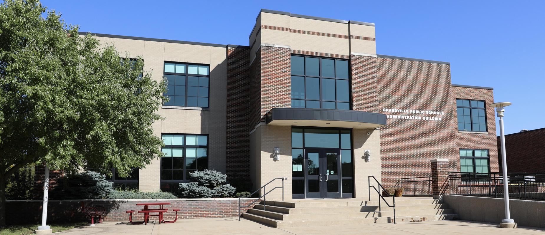 Administration building exterior facade with leafy green tree on left on a sunny day