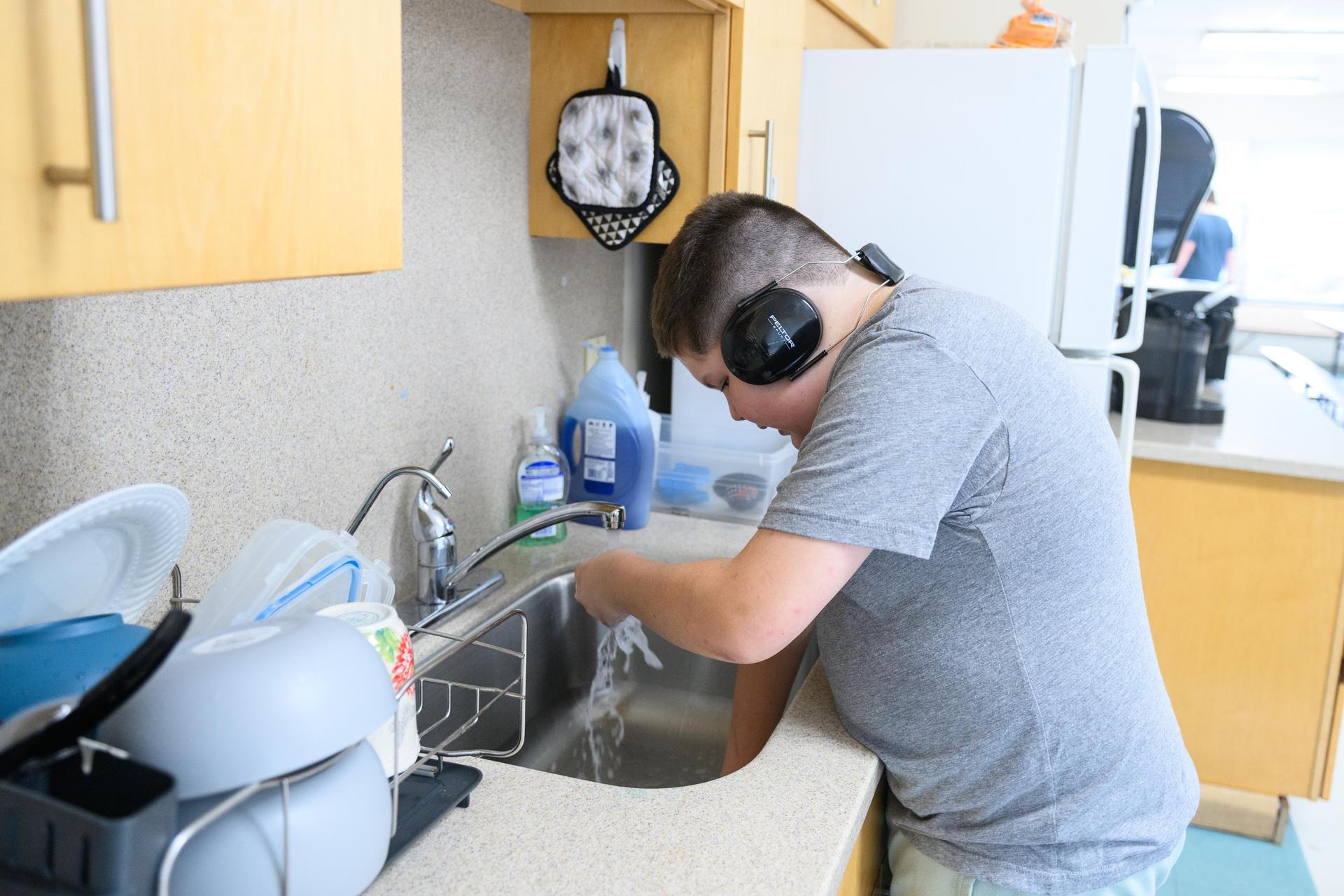 Student at sink washing hands.