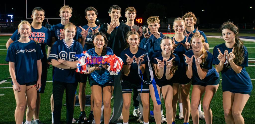 DSD group girls powderpuff football posing together on a sports field, smiling and gesturing.