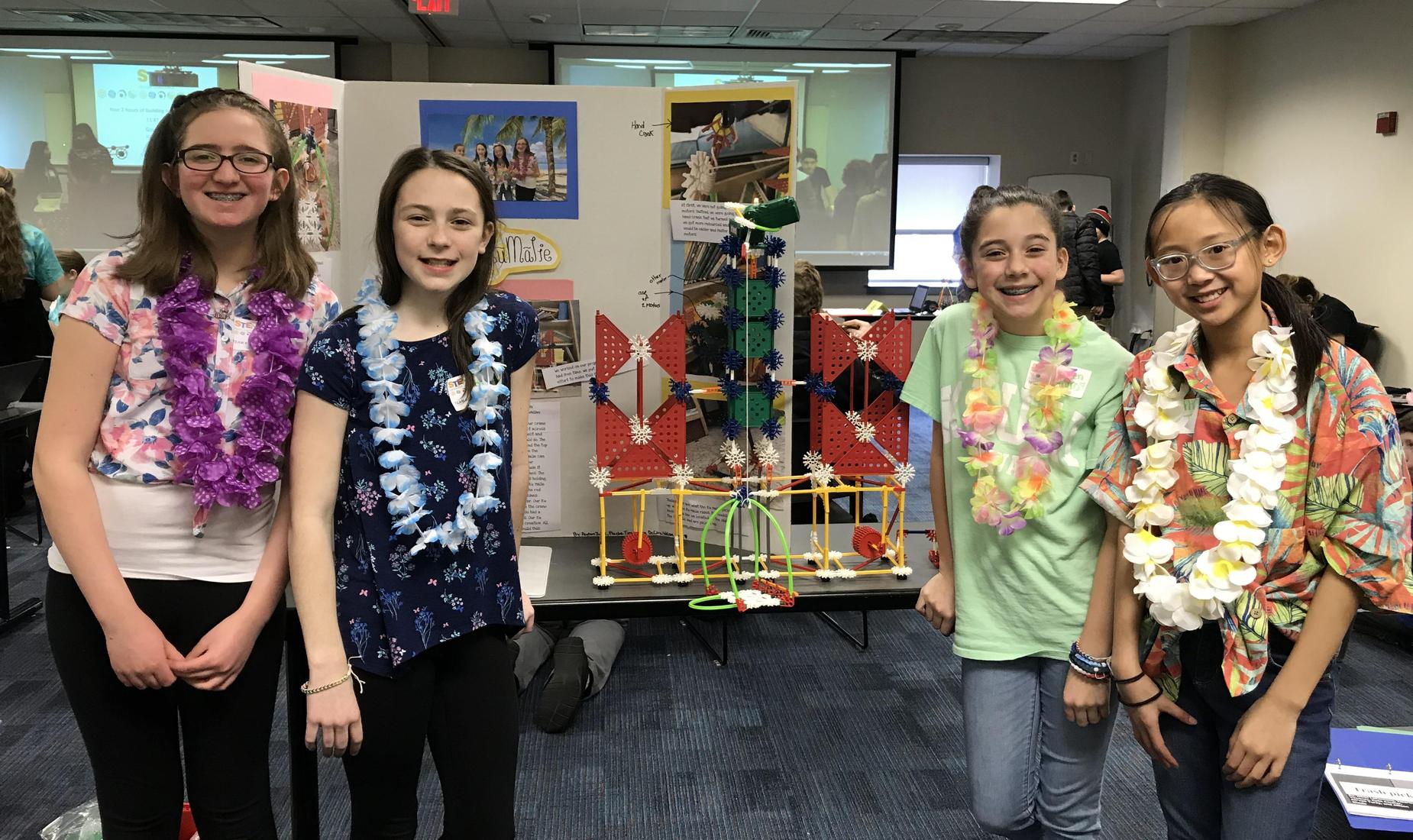 4 girls in colorful shirts with lays hanging on their neck showing their project from the K'Nex Challenge