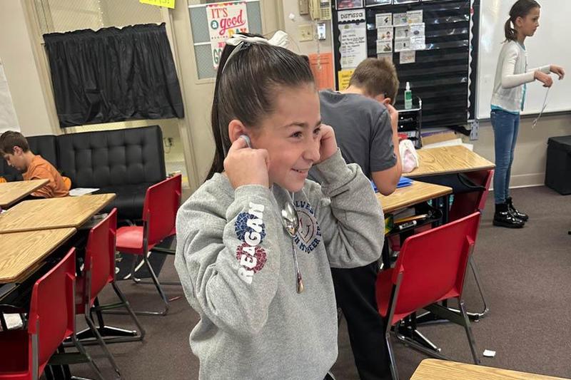 Reagan Savinda tests how a metal spoon transfers energy through vibrations