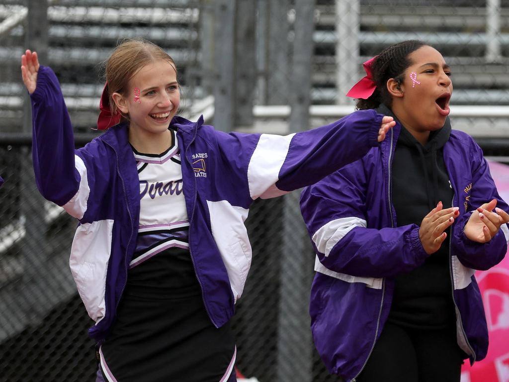 Two cheerleaders cheering on the sidelines.
