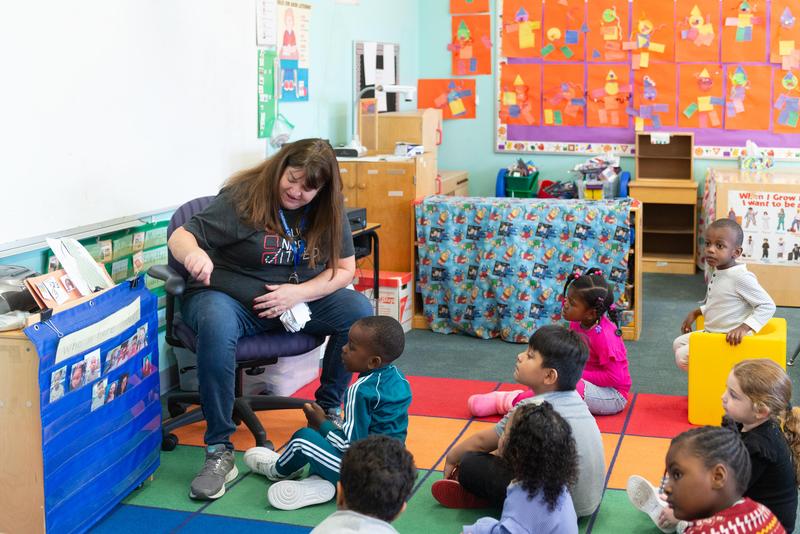 Educator reads a book to a group of preK students