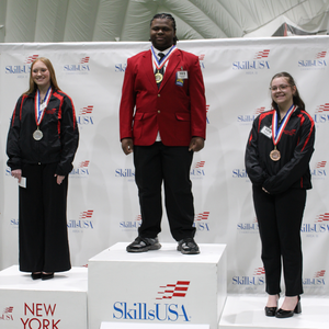 Three students on stacked podium of 1st, 2nd, and 3rd place