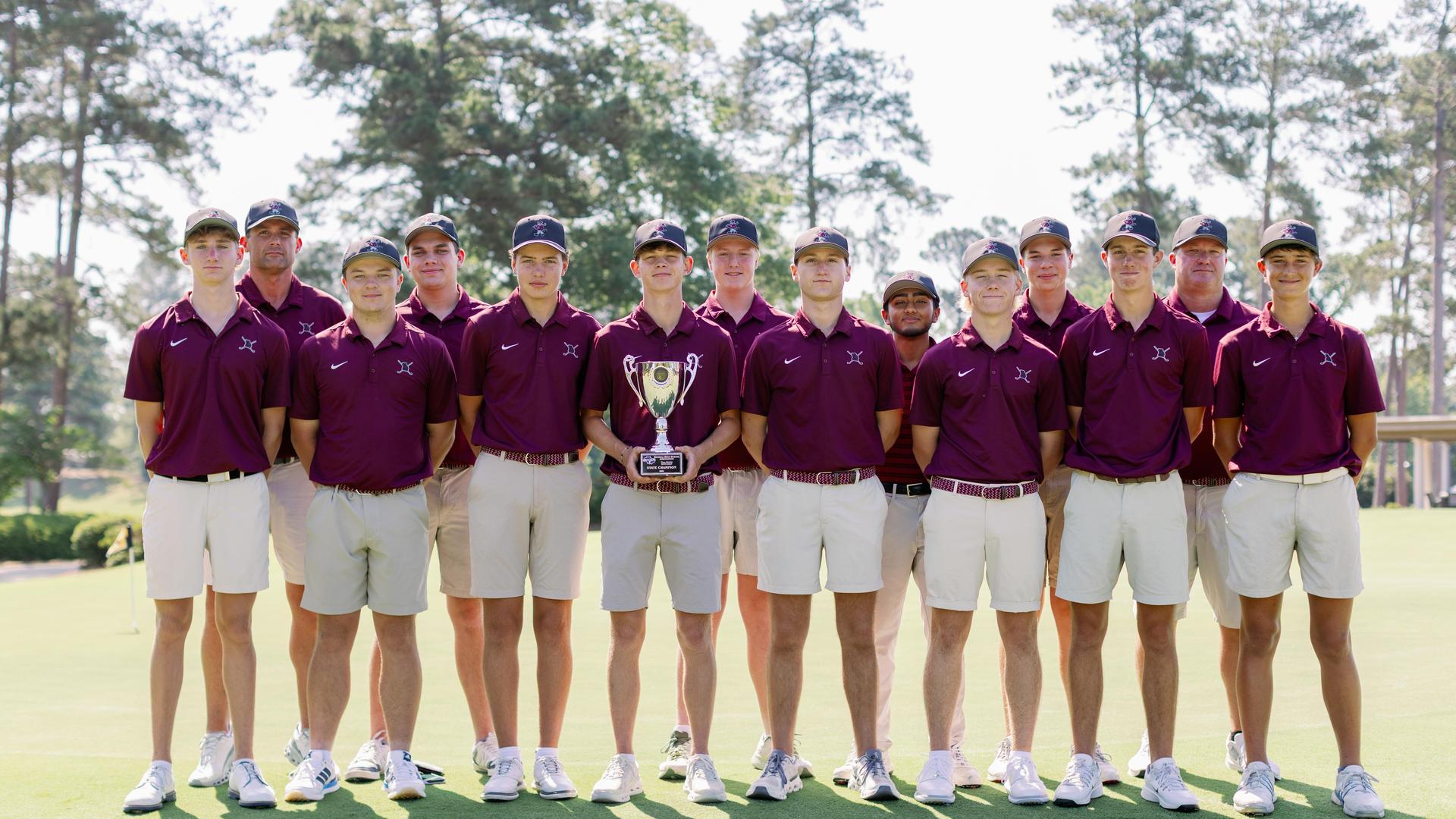A group of 13 young men in golf attire holding a trophy on a sunny golf course.