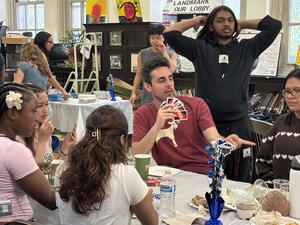 A mix of students engage in conversation around tables with refreshments and decorations.