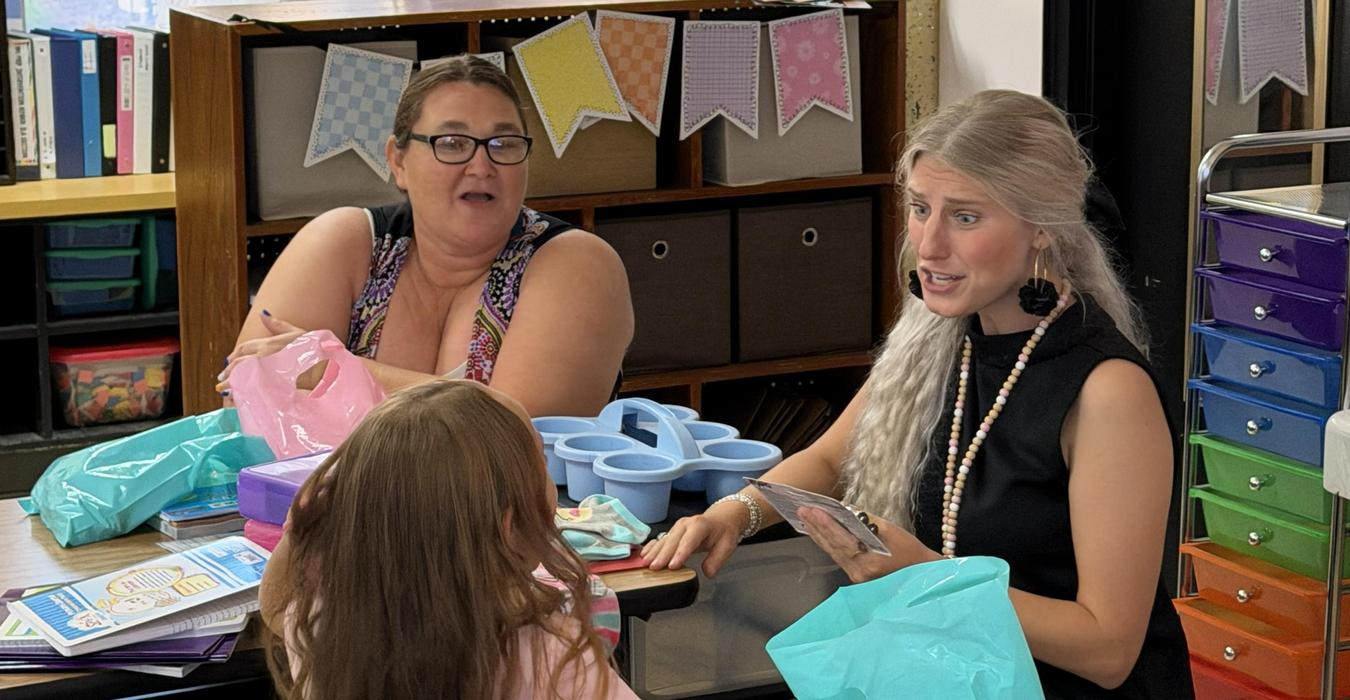 Two adults and a child engaging at a table filled with supplies.