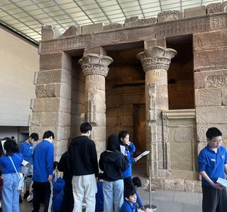 A group of students exploring an ancient Egyptian temple replica with towering columns.