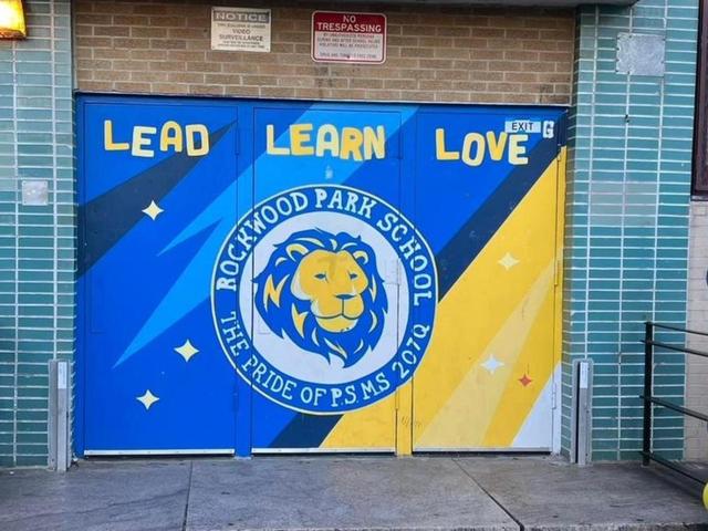 Colorful mural on a school entrance with a lion emblem and inspiring words.