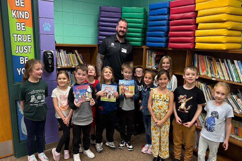 Scott Watkins (back) with a group of 1st-graders who are holding up some of his published books