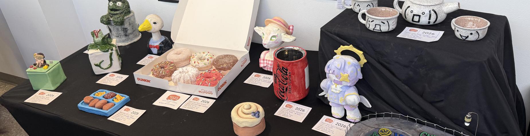 Table displaying various artistic sculptures and a box of colorful donuts.