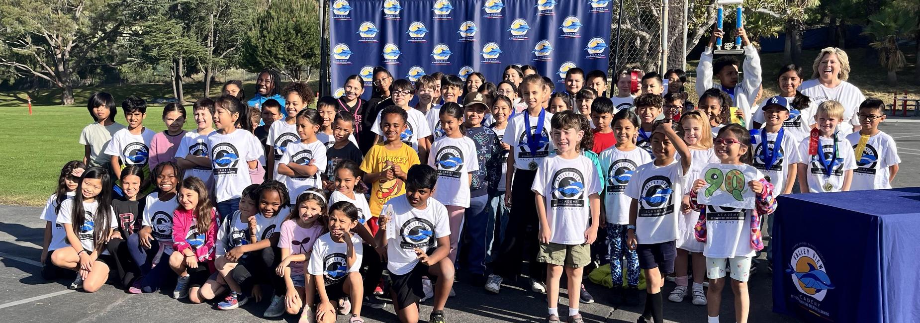 Large group of children and adults celebrating with trophies and shirts.