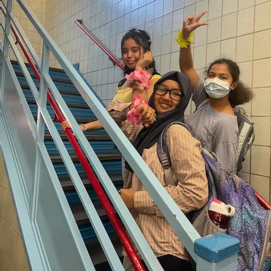 three students posing together on a stairwell