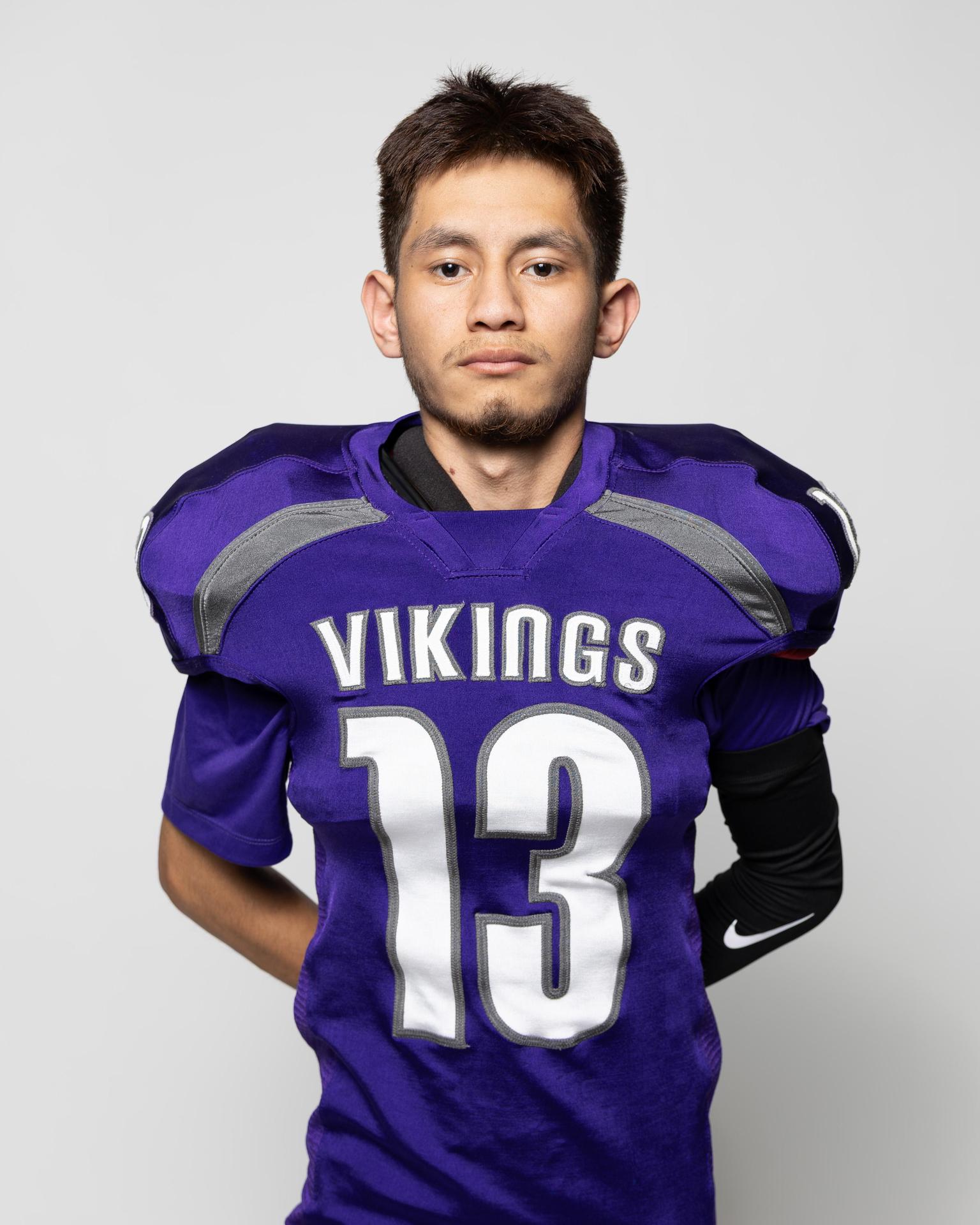 Young athlete in a purple football jersey with the number 13, standing confidently.