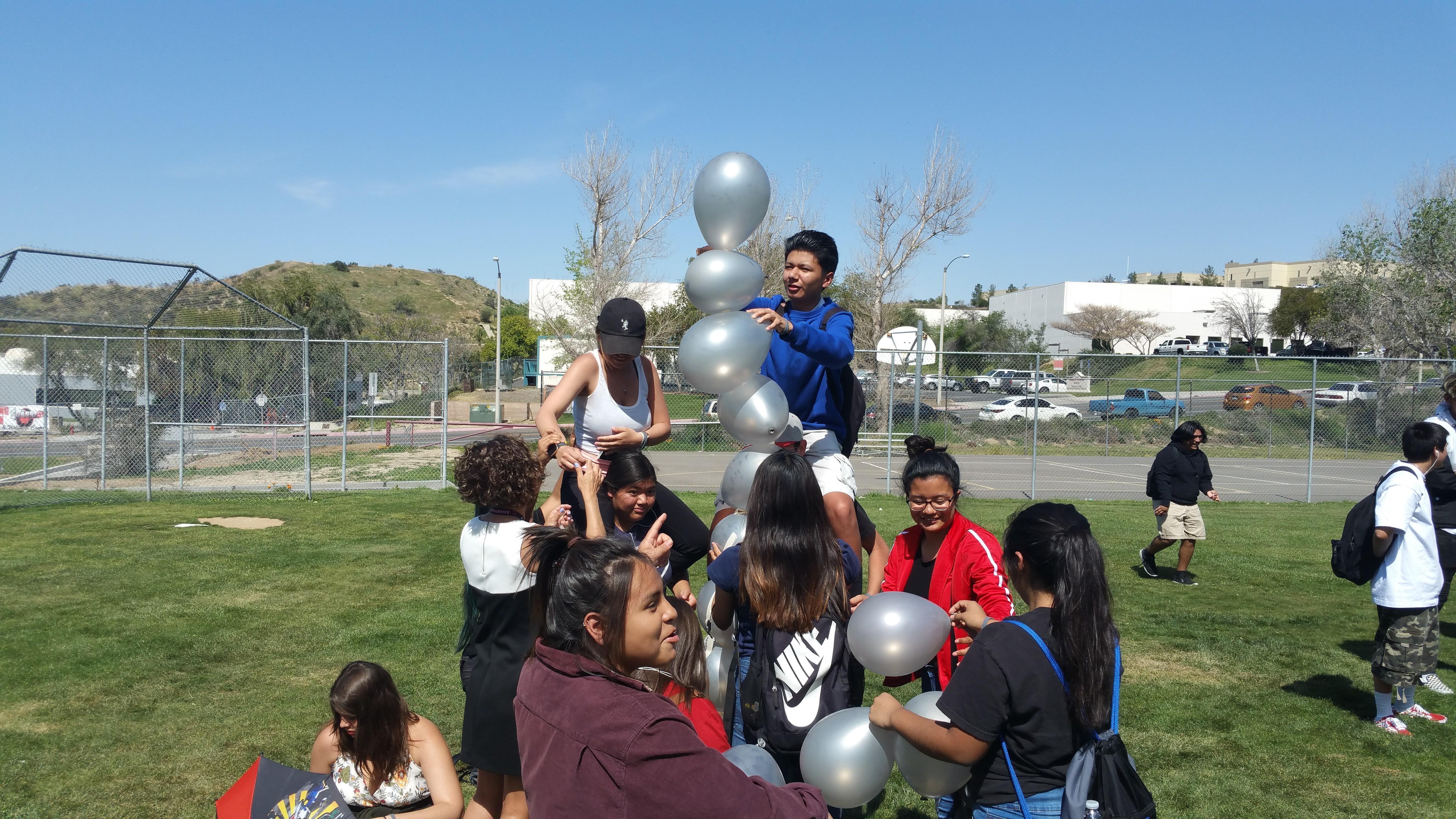 a group of students on the school athletic fields building a balloon arch