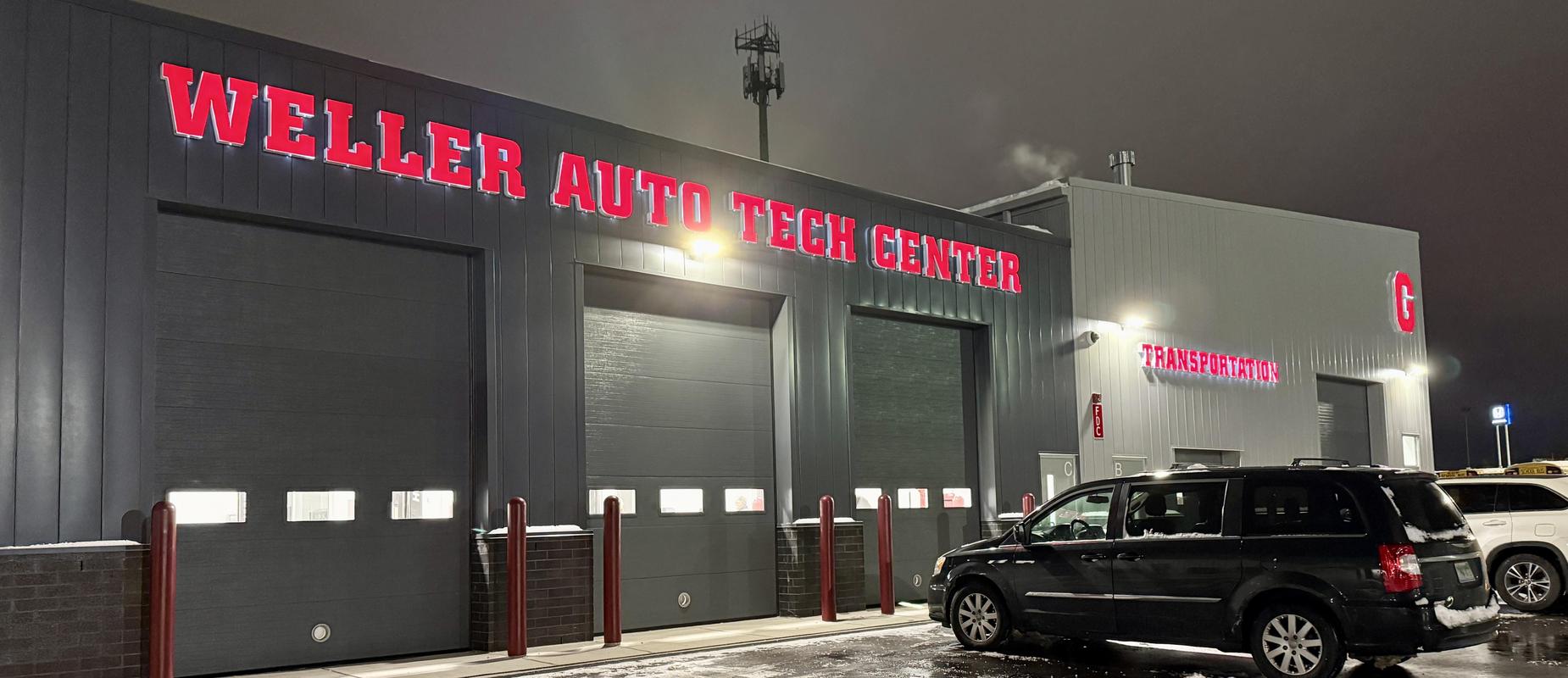 Weller Auto Tech Center exterior at night with three garages closed and cars outside