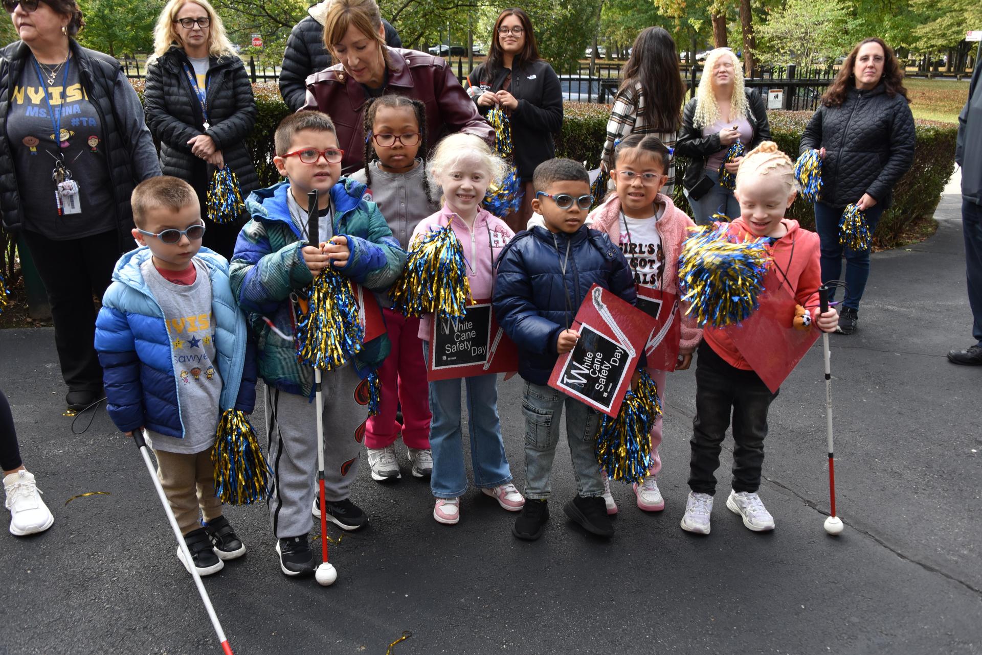 kids are outside holding their white canes 