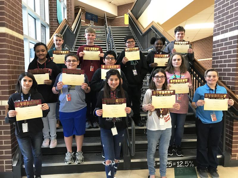 group of 13 students pose on steps with Student of the Month certificates