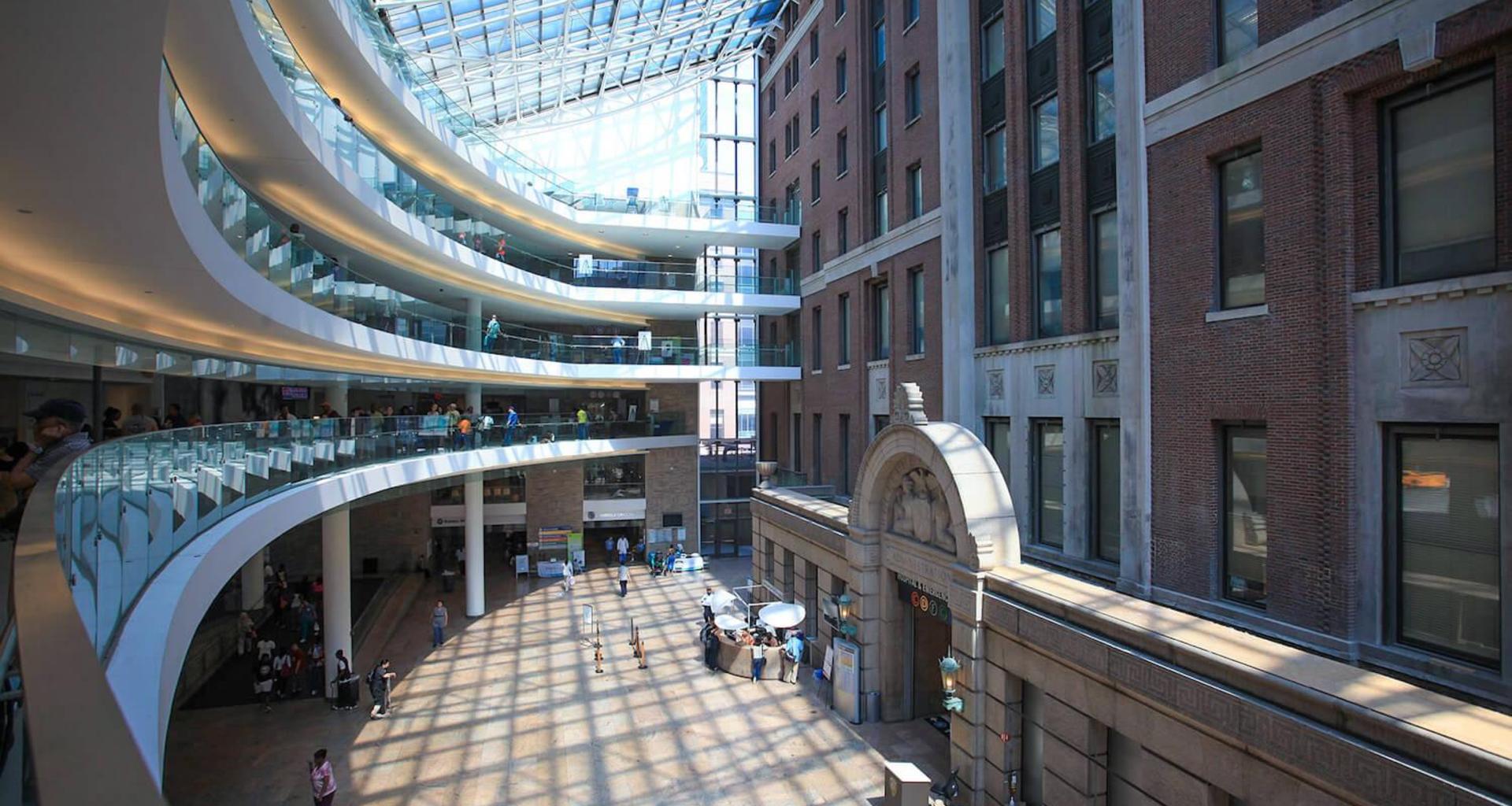 Modern atrium with curved glass architecture and people walking below.