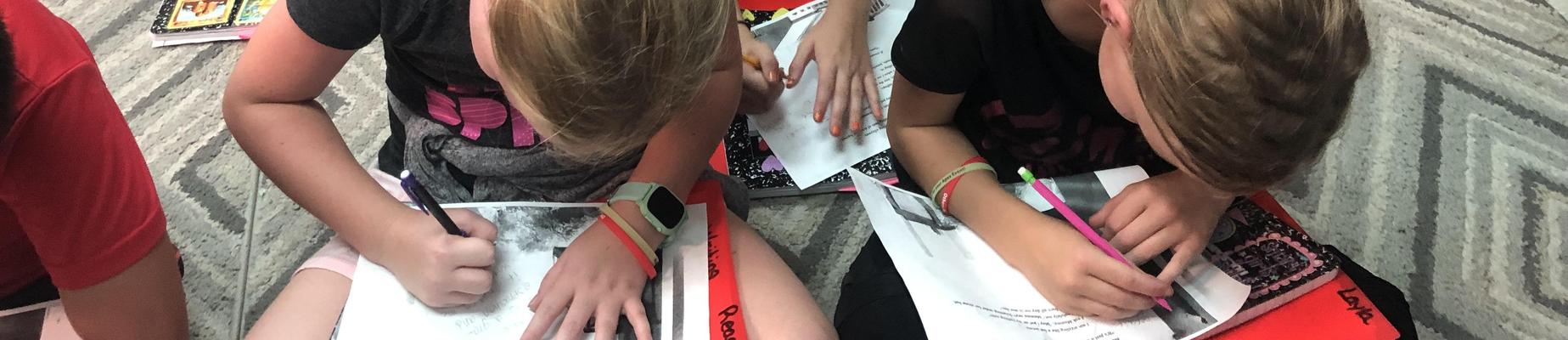 2 girls writing on notebooks
