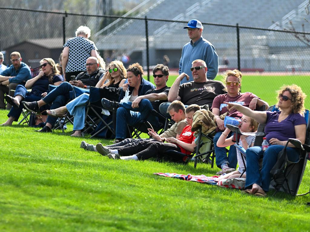 Parents on the sidelines watching a middle school sporting event.