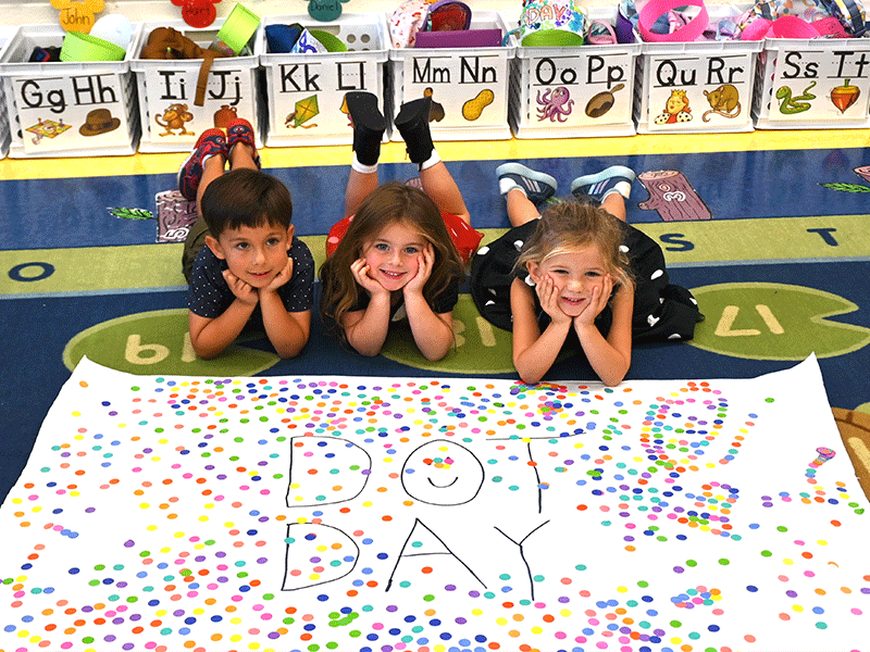 Three students laying on the floor with Dot Day Poster