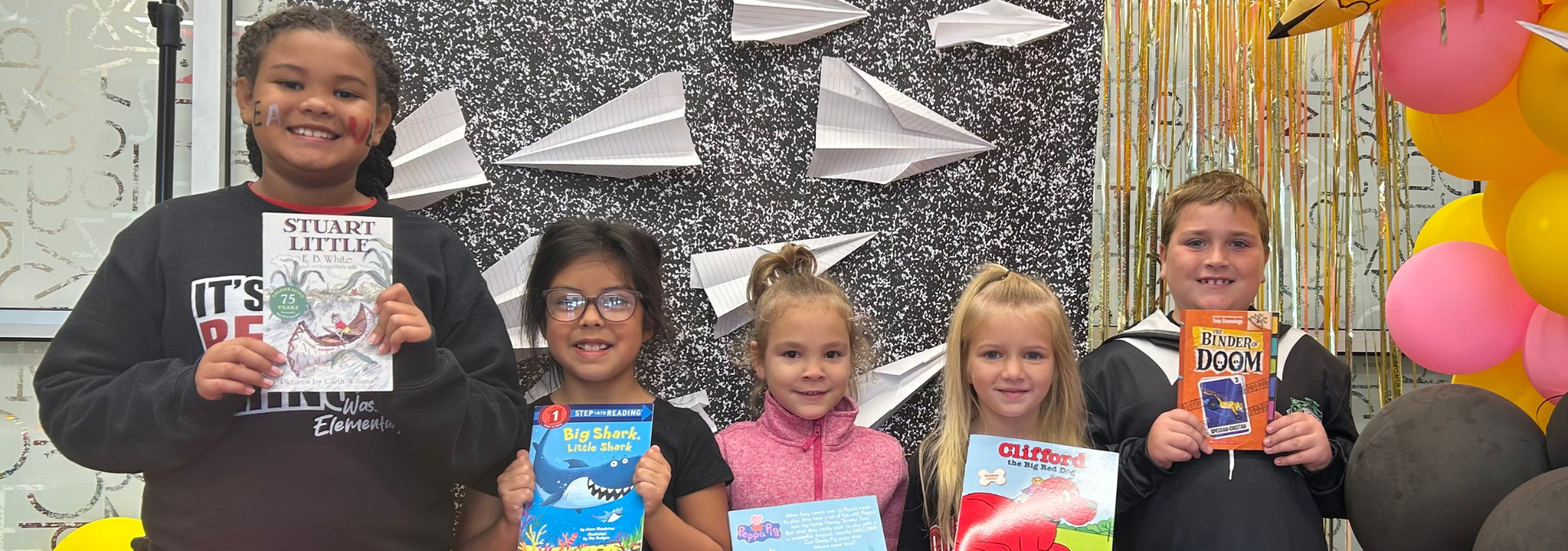 Five kids posing with various children's books in front of a decorative backdrop. Wasson Book Winners!