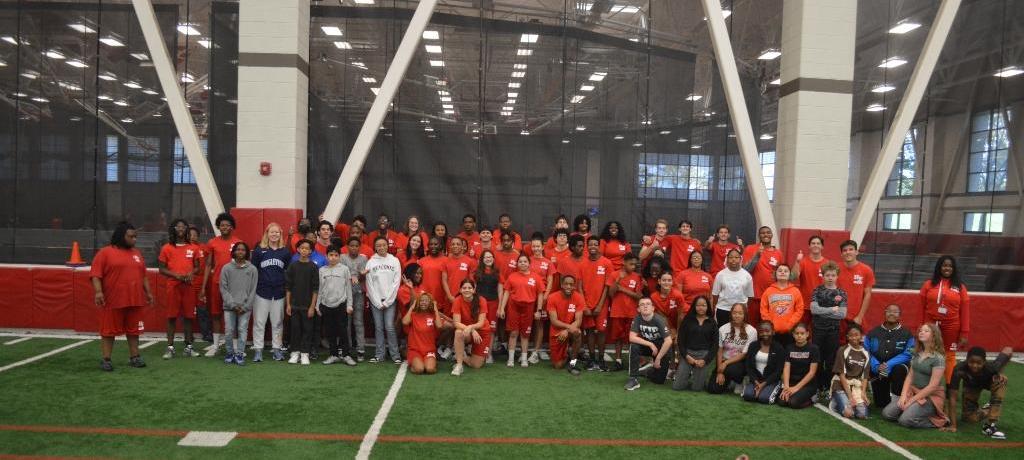 large group of high school and junior high students pose for a group photo in high school field house
