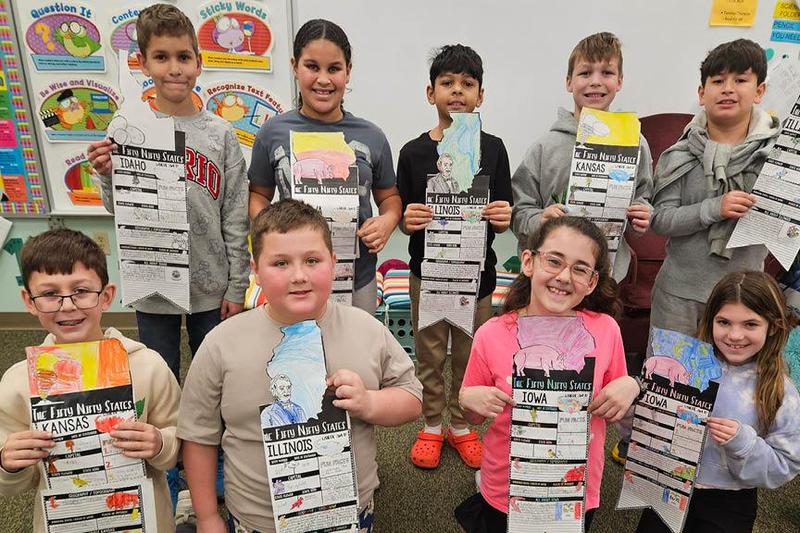 Third-grade students hold up their state reports, including (front) Aidan Simak, Gavin Chamberlain, Leah Yeager, Kylee Guarino, (back) Jonah Jones, Madison Laird, Malachi Krautz, Milo Lemmon, and Leo Molina