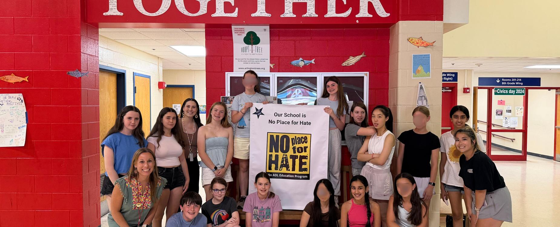 Students and Principal standing together holding a "No Place for Hate" sign
