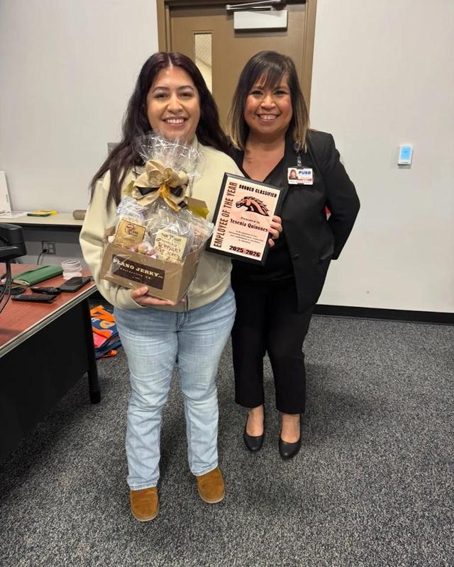Yesenia Quinones holds her Butterfield Charter School Classified Employee of the Year award and gift basket alongside a district administrator.