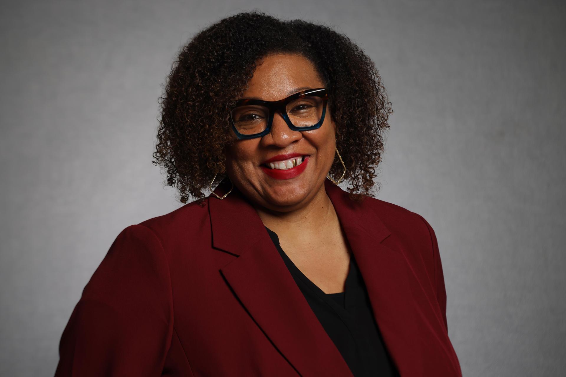 headshot of michelle rhodes wearing a maroon blazer