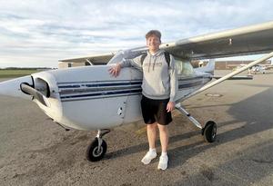 a boy standing beside a small airplane