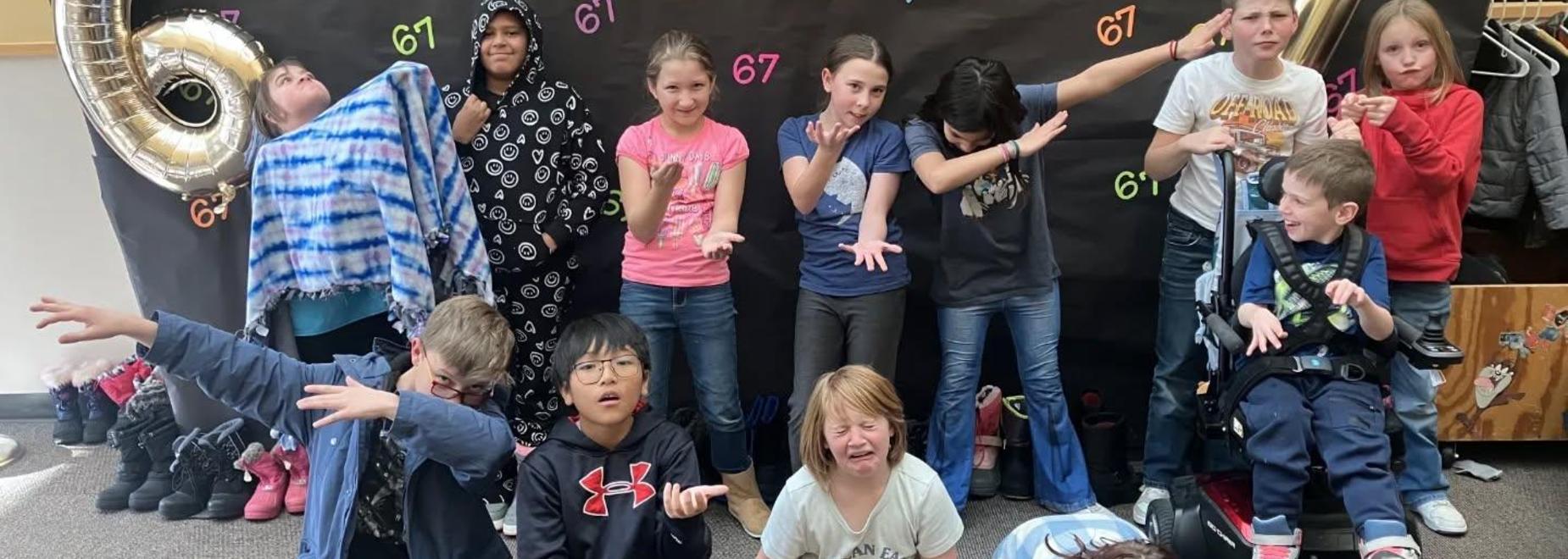 Students making silly poses in front of a birthday backdrop.
