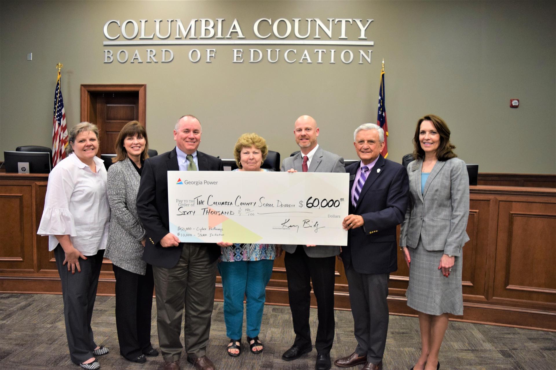 group smiling holding big check