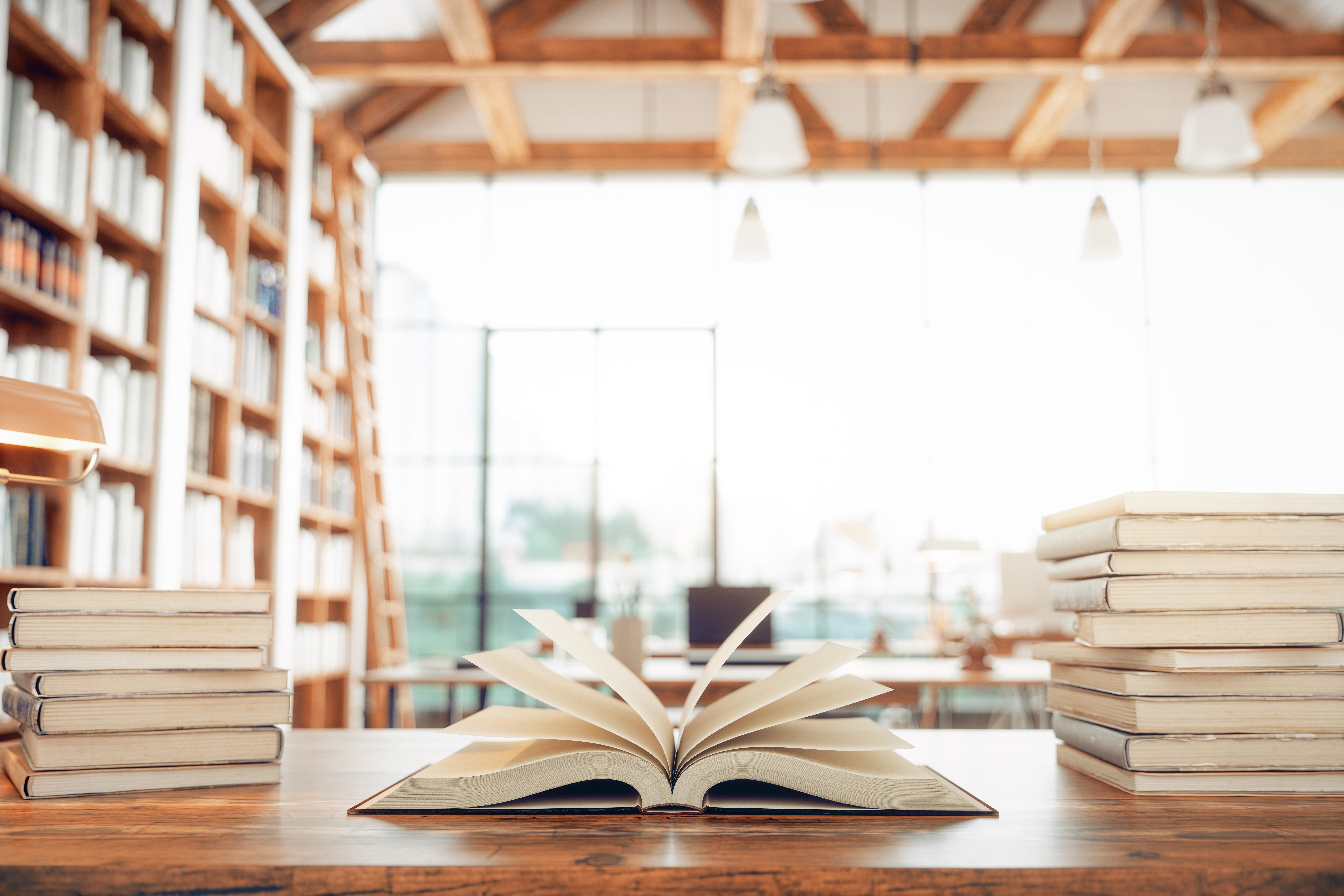 An opened books sitting on a desk in a library.