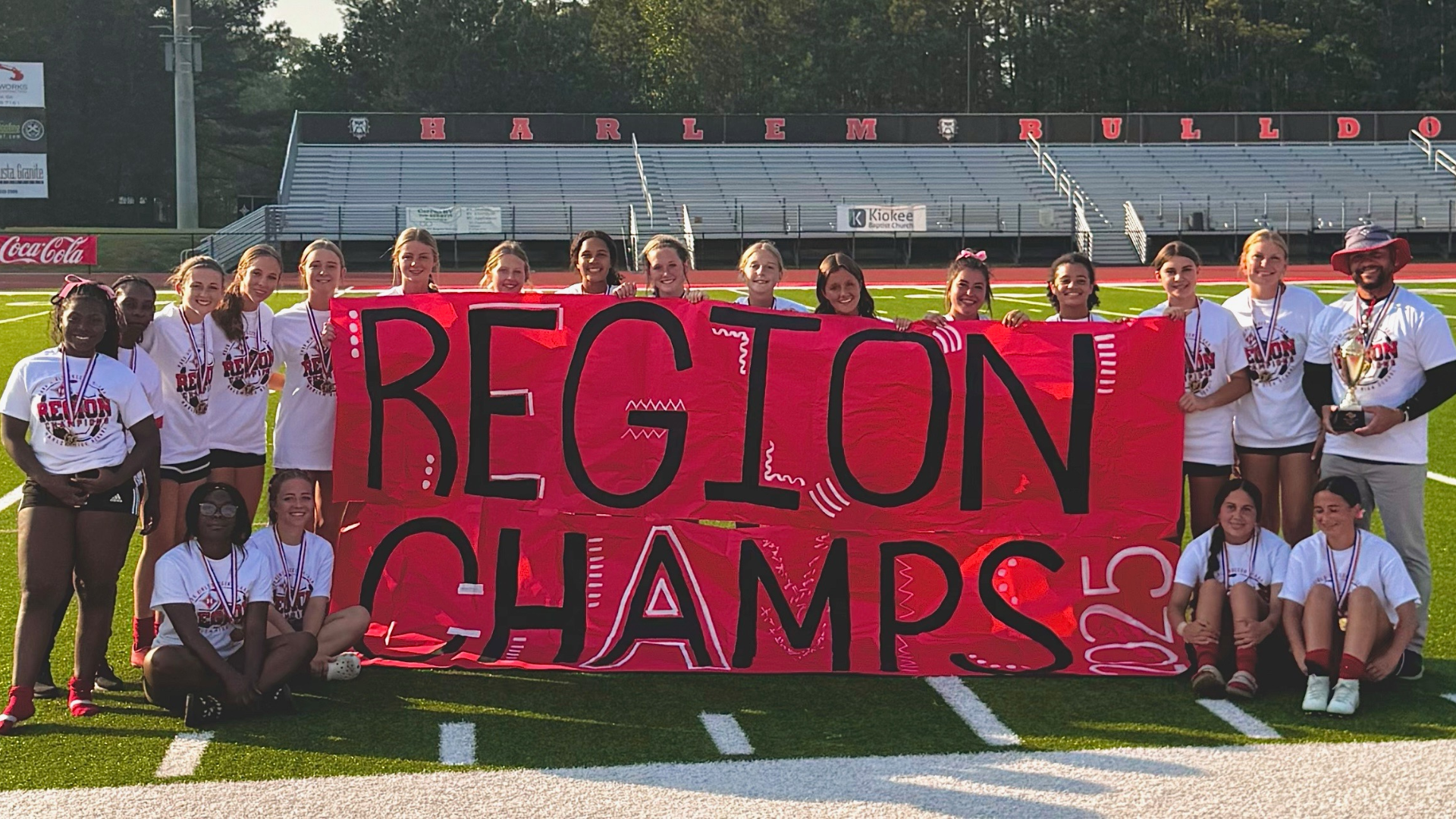 A group of cheering athletes hold a large banner celebrating their regional championship.