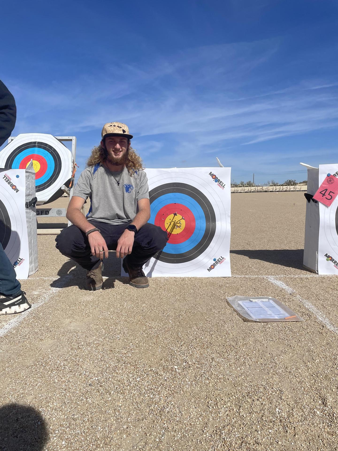 archery participant posing next to target