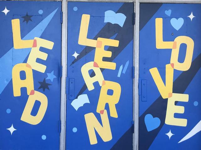 Colorful mural with the words 'LEAD,' 'LEARN,' and 'LOVE' on blue doors.