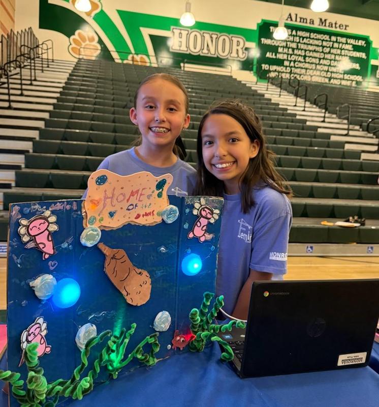 two girls smile and how off their stem project.