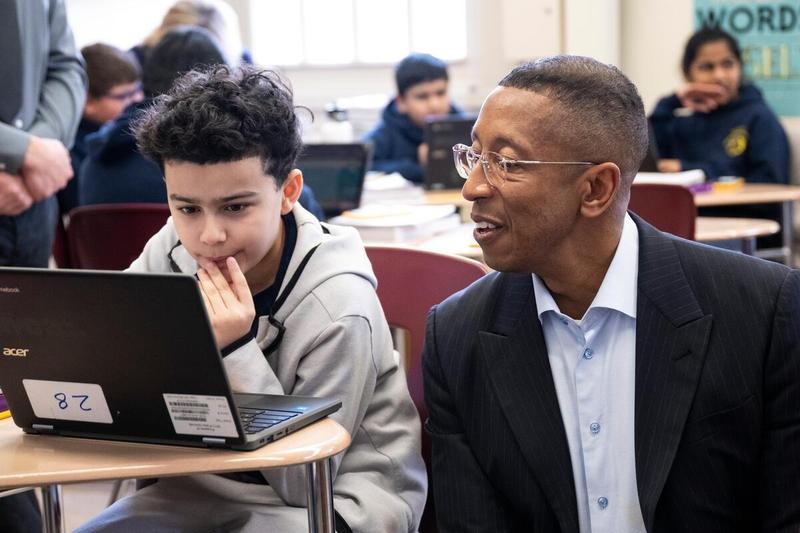 Allan Golston sits down with a student at P.S. 083 Donald Hertz as he works through a math problem, highlighting how teachers are using tech-enabled tools to better understand student learning.