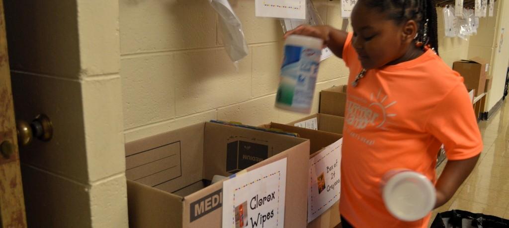 Girl sorts school supplies for classroom.