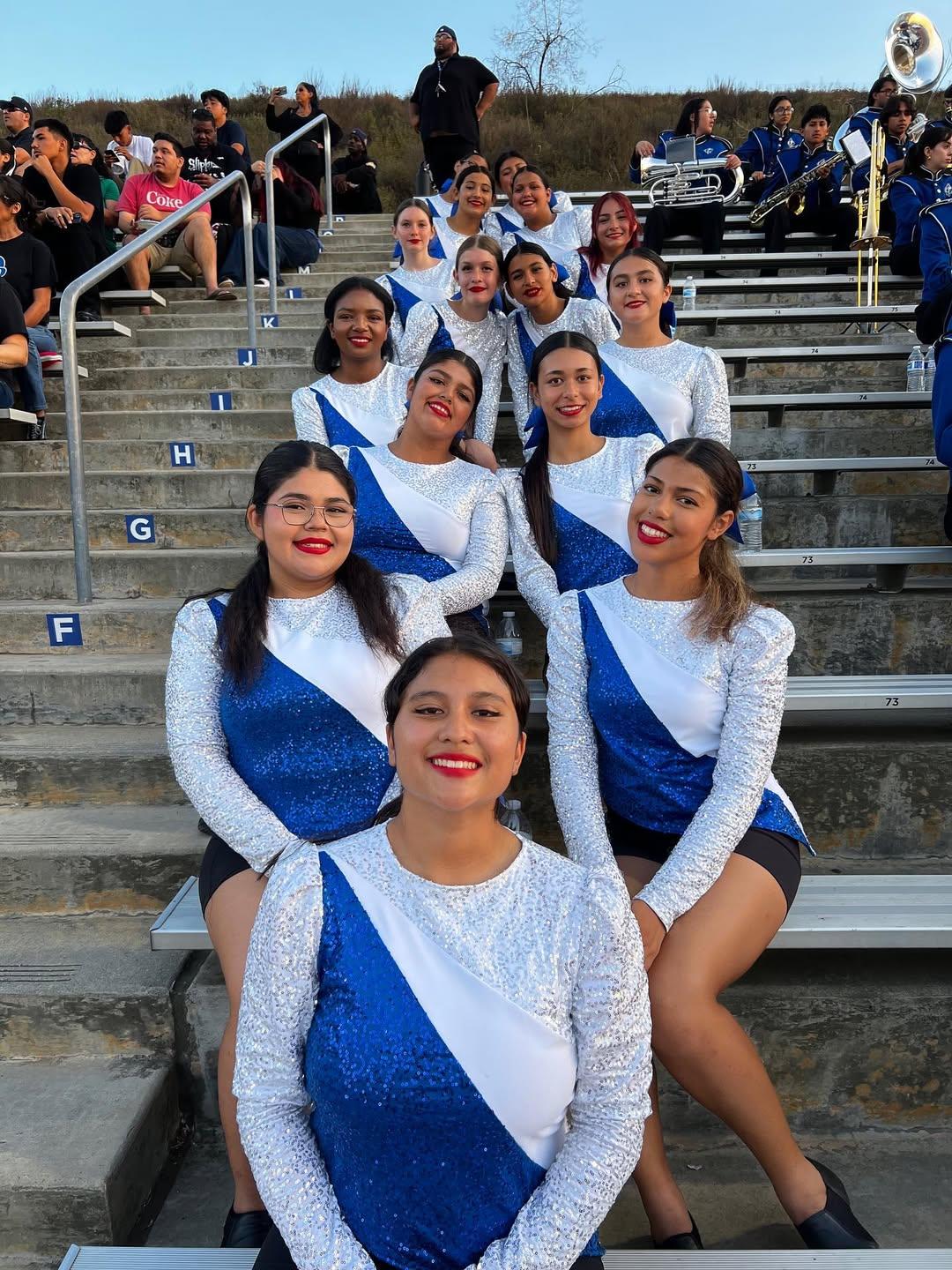 our drill team in a row sitting at the bleachers during a break