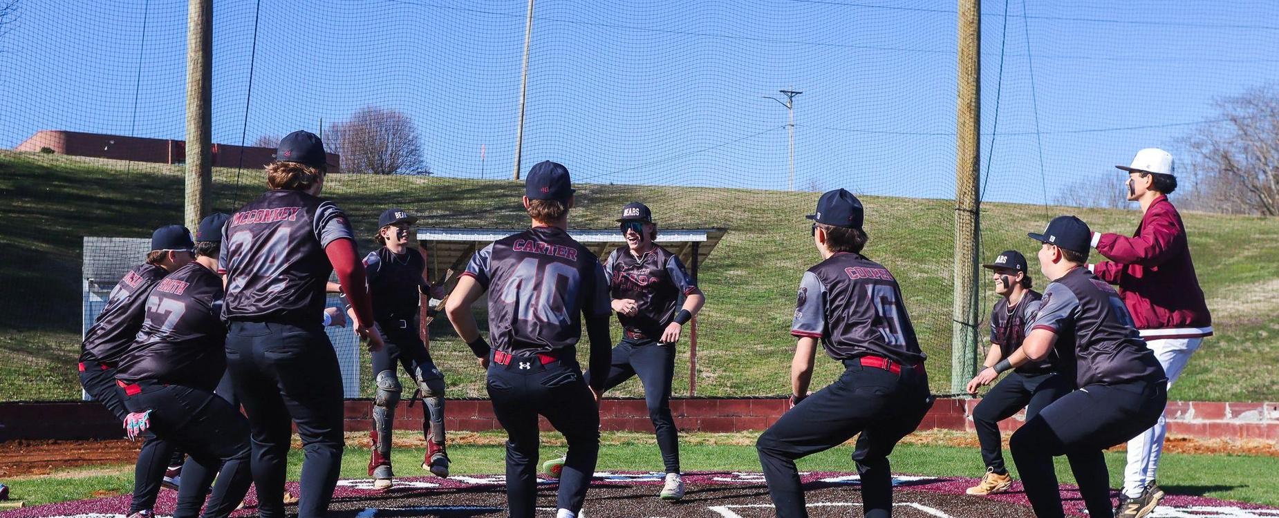 A group of baseball players warming up on a field near home plate.